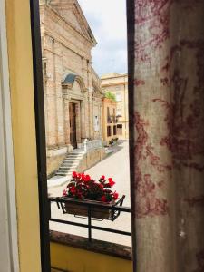 ein Fenster mit einer Schüssel roter Blumen auf einer Straße in der Unterkunft Don Pasquale Picciano- PESCARA-ABRUZZO in Picciano
