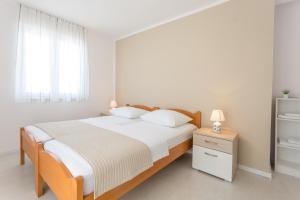 biała sypialnia z dużym łóżkiem i oknem w obiekcie Apartments Gordana Jeličić w Hvarze