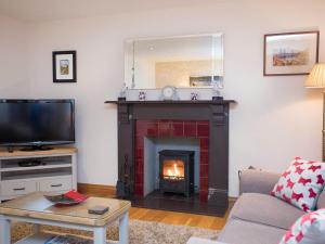 a living room with a fireplace and a tv at Hen Stabl Llandwrog in Llandwrog