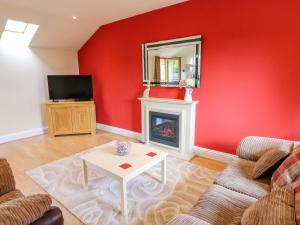 a living room with a red wall and a fireplace at Stonecroft Lodge in Belper