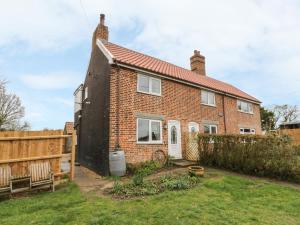 a brick house with a fence in the yard at 2 Hillside Cottages in Ipswich