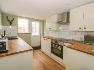 a kitchen with white cabinets and wooden floors at 2 Hillside Cottages in Ipswich