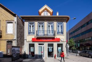 eine Frau, die vor einem Gebäude eine Straße entlanggeht in der Unterkunft Casa do Papel - Charm in Matosinhos in Matosinhos