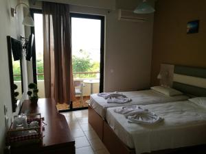 a hotel room with two beds and a large window at Golden days in Afantou