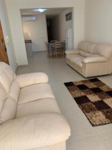 a living room with two white couches and a kitchen at Stresa Court Apartments in St. Julianʼs