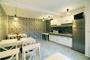 a kitchen with white cabinets and a table and a refrigerator at Select House in Sibiu