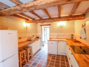 a kitchen with white appliances and wooden ceilings at Jasmine Cottage in Belper