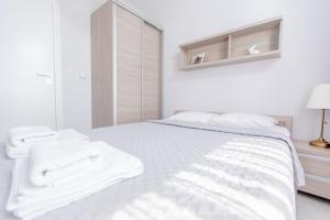 biała sypialnia z białym łóżkiem i ręcznikami w obiekcie Resort Apartamenty Klifowa Rewal 23 w Rewalu +32 zdjęcia