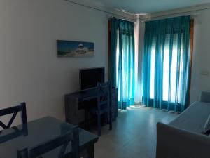 a living room with blue curtains and a television at Colores de Zahara in Zahara de los Atunes