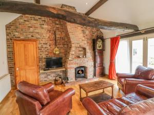 a living room with leather furniture and a brick fireplace at Forge Cottage in Gainsborough