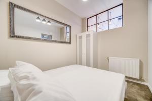 a white bedroom with a mirror and a bed at Rint - Centrum Lipowa Street in Białystok