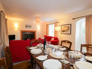 a dining room with a table and a red couch at Tigh Fasgaidh in Dornie