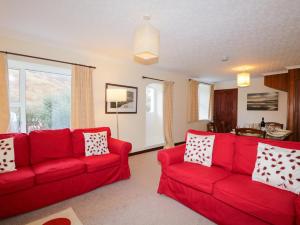 a living room with two red couches and a window at Tigh Fasgaidh in Dornie
