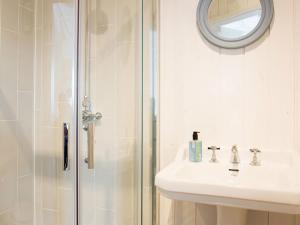 a bathroom with a shower and a sink and a mirror at Lligwy Beach Cottage in Penrhos-Lligwy