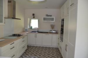 a white kitchen with white cabinets and a sink at La Remise 4 étoiles in Saint-Hilaire-de-Mortagne
