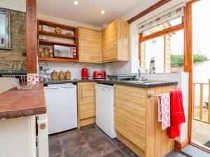 a kitchen with wooden cabinets and white appliances at Cedarwood Cottage in Winkleigh +7 photos