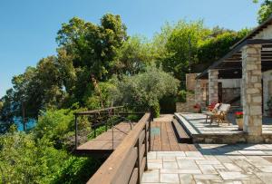 un jardín con terraza de madera y un edificio en Pelion BNB Luxury homes, en Damouchari