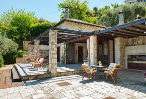 a patio with chairs and a table in front of a house at Pelion BNB Luxury homes in Damouchari