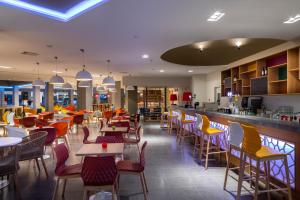 a restaurant with tables and chairs and a bar at Leonardo Laura Beach & Splash Resort in Paphos