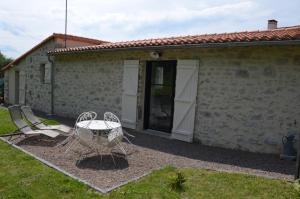 a table and chairs in front of a building at La Remise 4 étoiles in Saint-Hilaire-de-Mortagne