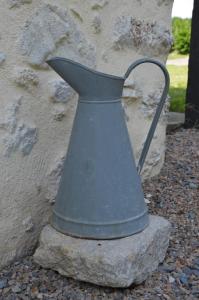 a metal vase sitting on a rock next to a wall at La Remise 4 étoiles in Saint-Hilaire-de-Mortagne