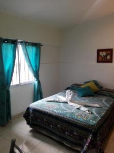 1 dormitorio con 1 cama con cortinas azules y ventana en Tierra del sol en Guaymallén