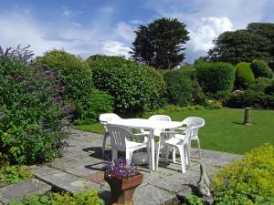 a white table and chairs in a garden at Mor Edrin in Criccieth