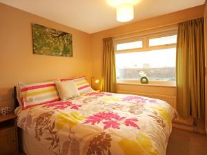 a bedroom with a bed with a colorful comforter and a window at Mor Edrin in Criccieth