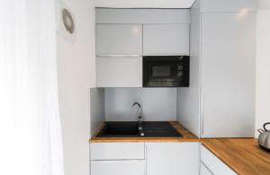 a kitchen with white cabinets and a microwave at St Stephens Road Apartment in Norwich