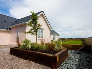 une maison avec un arbre dans une boîte en bois dans l'établissement Lligwy Beach Cottage, à Penrhos-Lligwy