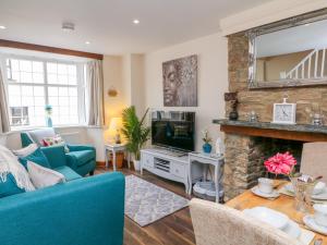 a living room with a blue couch and a fireplace at Cedarwood Cottage in Winkleigh