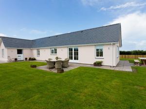 Casa blanca con un gran patio con césped verde en Lligwy Beach Cottage, en Penrhos-Lligwy