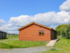 a small wooden cabin in a grassy field at Oak Lodge in York