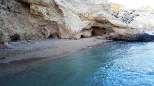 a beach with blue water and a rocky cliff at Limeri Traditional Guest House in Monólithos