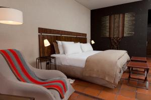 a hotel room with a bed and a chair at Nayara Alto Atacama in San Pedro de Atacama