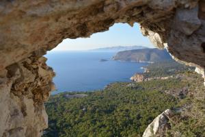 a view of the ocean seen through a hole in a rock at Limeri Traditional Guest House in Monólithos