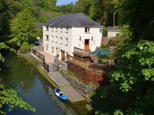 a house with a small boat in a river at Melin y Coed in Menai Bridge