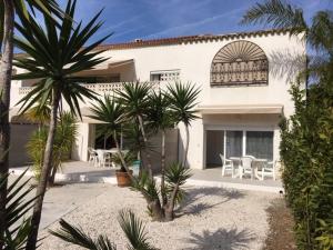 a white house with palm trees in front of it at Appartements Les Pesquiers 2 Hyères Plage in Hyères