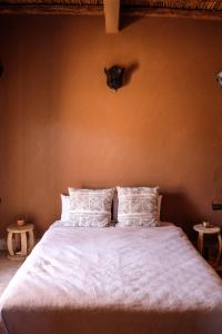 a bedroom with a bed with white sheets and pillows at Kasbah Aitisfoul in Tagounite