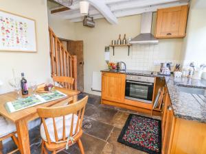 uma cozinha com armários de madeira e uma mesa e cadeiras em Rose Cottage em Skipton
