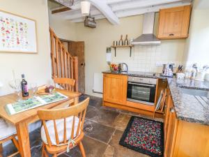 eine Küche mit Holzschränken und einem Tisch und Stühlen in der Unterkunft Rose Cottage in Skipton