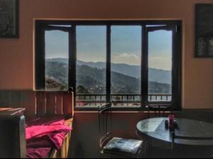 a room with a large window with a view of the mountains at Berg House Cafe and Hotel in Nagarkot