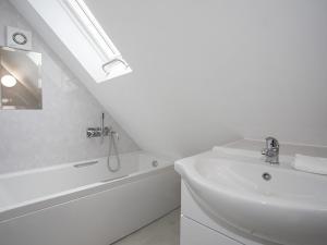a white bathroom with a sink and a bath tub at Pen Y Prys in Pentraeth