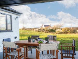 a table and chairs on a patio with a view of a field at Mwythus in Rhoscolyn
