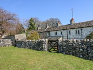 ein altes Steinhaus mit einer Steinmauer in der Unterkunft Rose Cottage in Skipton + 15 Fotos
