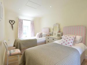 a bedroom with two beds and a dresser and a mirror at Penrhyn Farm in Penrhos-Lligwy