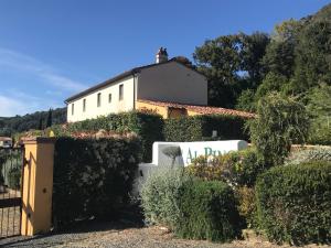 ein weißes Haus mit einem Zaun und Büschen in der Unterkunft Casa Vacanze "Casale al Pino" in Riparbella