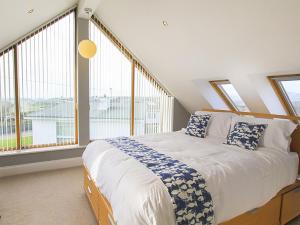 a bedroom with a large bed and large windows at Penmynydd in Trearddur