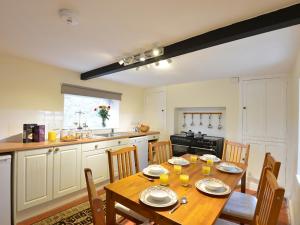 a kitchen with a wooden table with chairs and a dining room at Pentreheulyn in Bodewryd