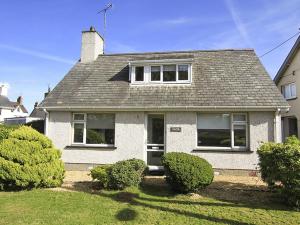 a white house with a gray roof and bushes at Perthi in Morfa Nefyn